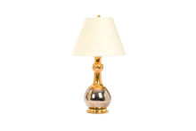Cameron table lamp in mixed luster glaze with gold on top of the form and platinum on bottom of the form, with a 23k gold base, brass double socket cluster, and off white vellum paper lampshade, on a white background.