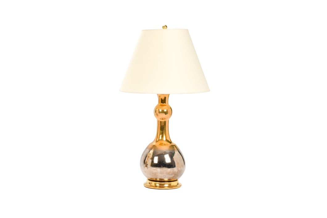 Cameron table lamp in mixed luster glaze with gold on top of the form and platinum on bottom of the form, with a 23k gold base, brass double socket cluster, and off white vellum paper lampshade, on a white background.