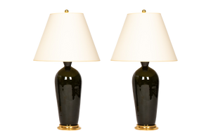 Pair of Seth table lamps in olive green glaze with 23k gold water gilt bases, brass double socket clusters, and off white vellum paper shades, on a white background.