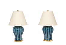 Pair of Douglas Table Lamp with Hand Slip Trailed Chevron Detail in Prussian Blue Glaze with 23k gold water gilt bases, brass double socket clusters, and off white vellum paper lamp shades, on a white background.